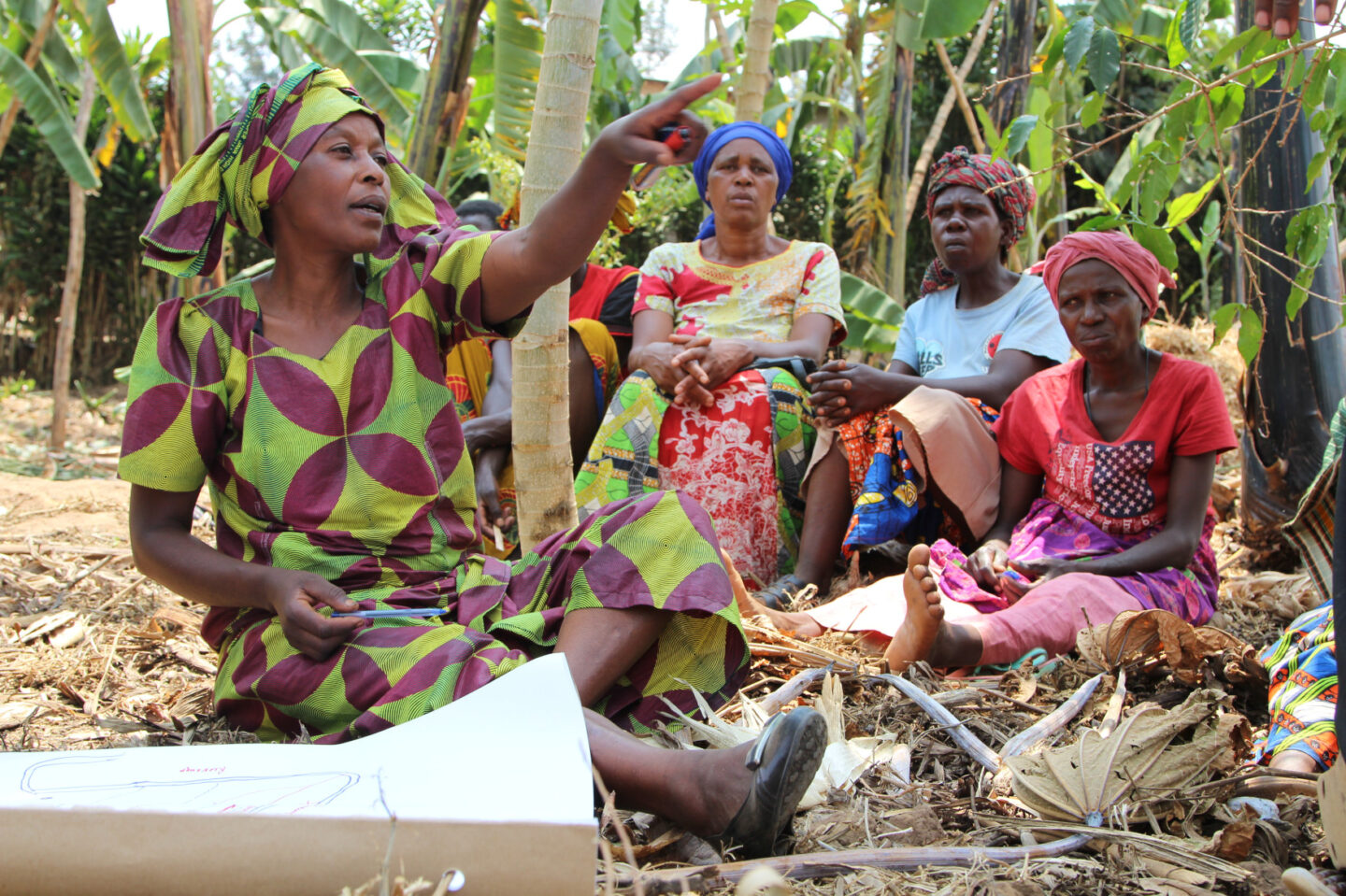 A group of women farmers work with a map on farmland in Rwanda