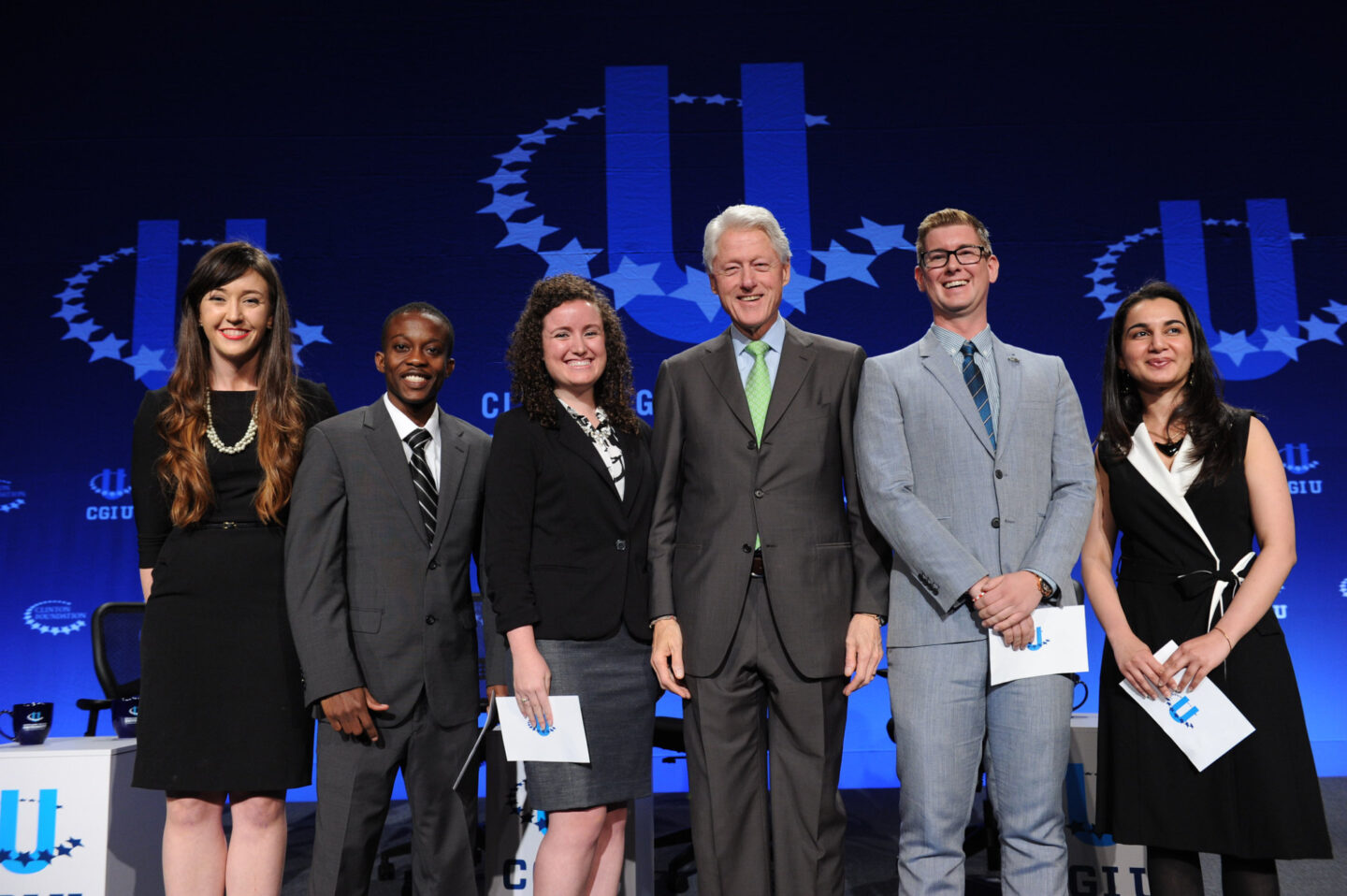 President Clinton takes a photo with student commitment-makers on stage