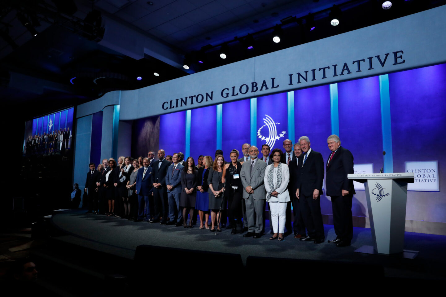 President Clinton takes a photo with commitment-makers on stage