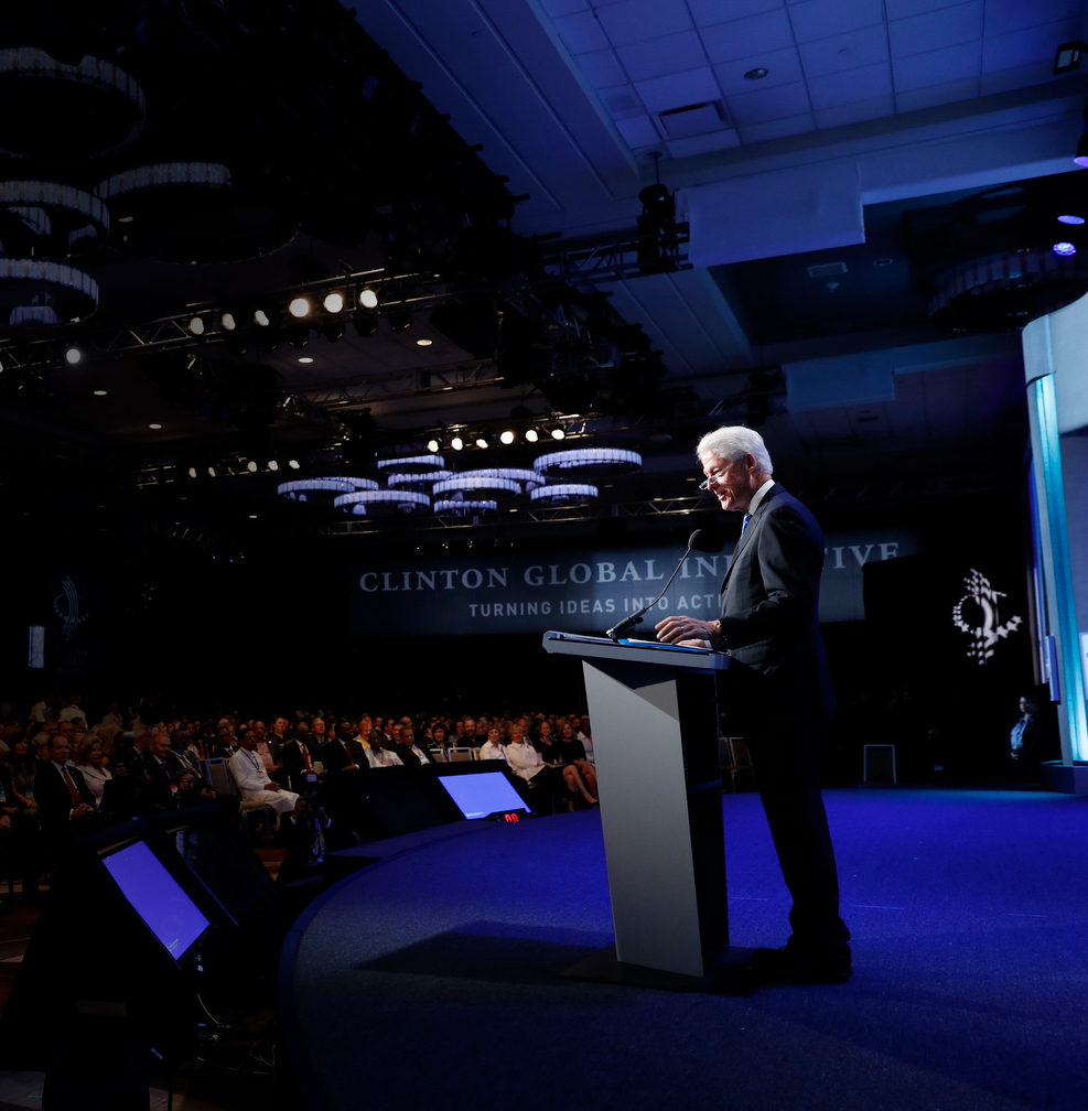 President Clinton stands onstage in front of a large crowd during a Clinton Global Initiative event