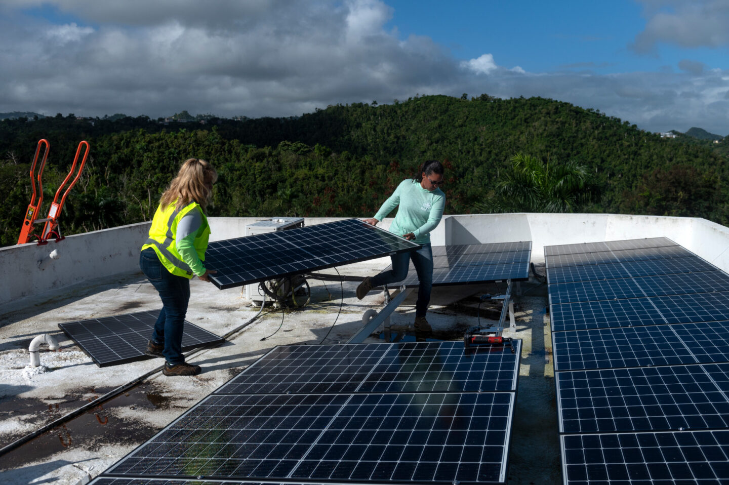 Workers install a solar panel on the roof of a house in Puerto Rico