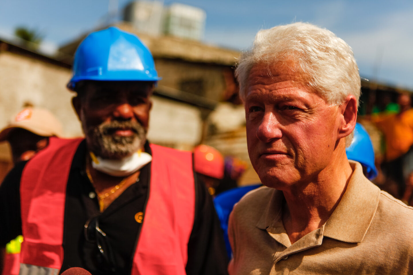 President Clinton stands with an individual wearing a hard hat and vest