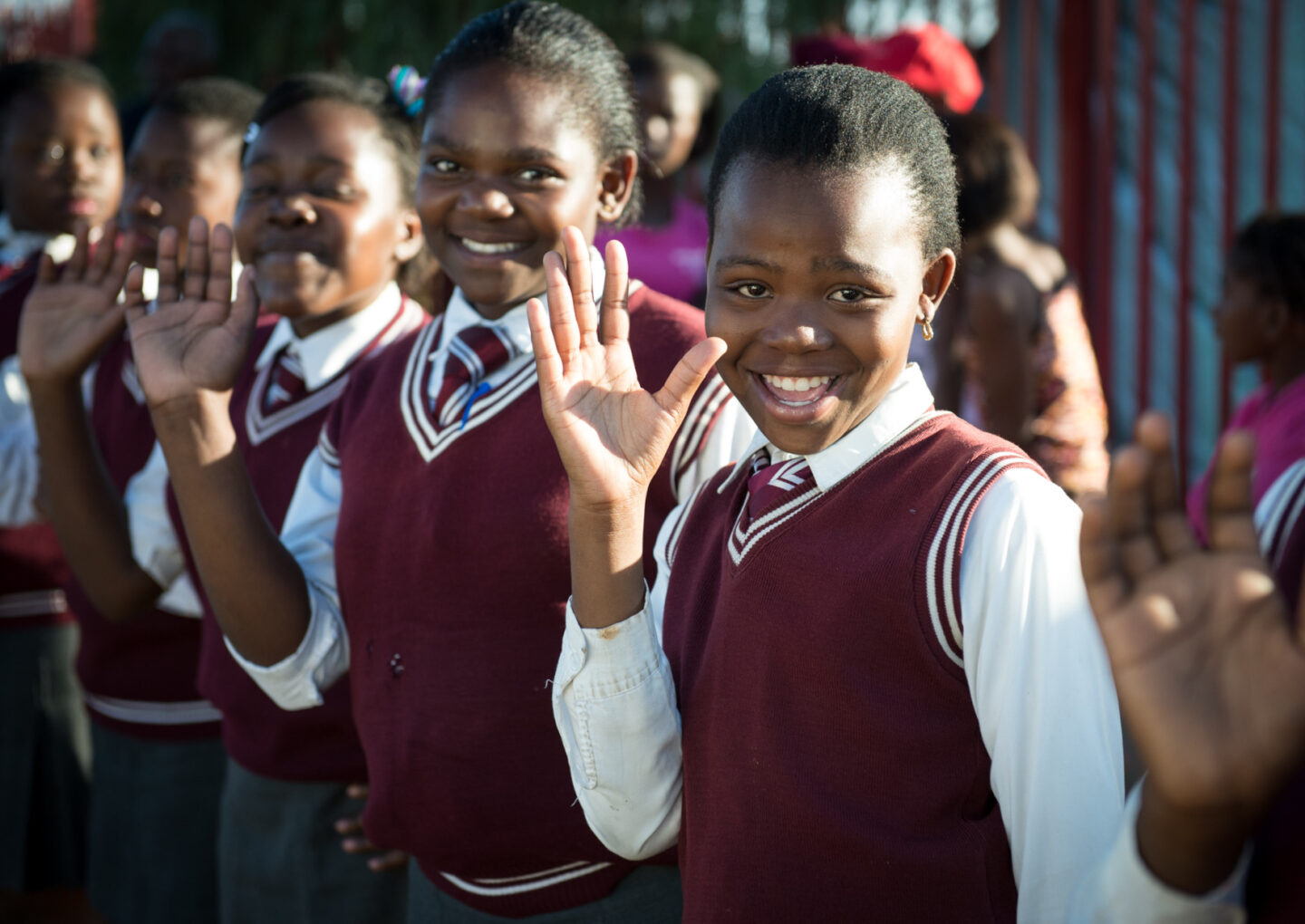 Several students in matching uniforms wave