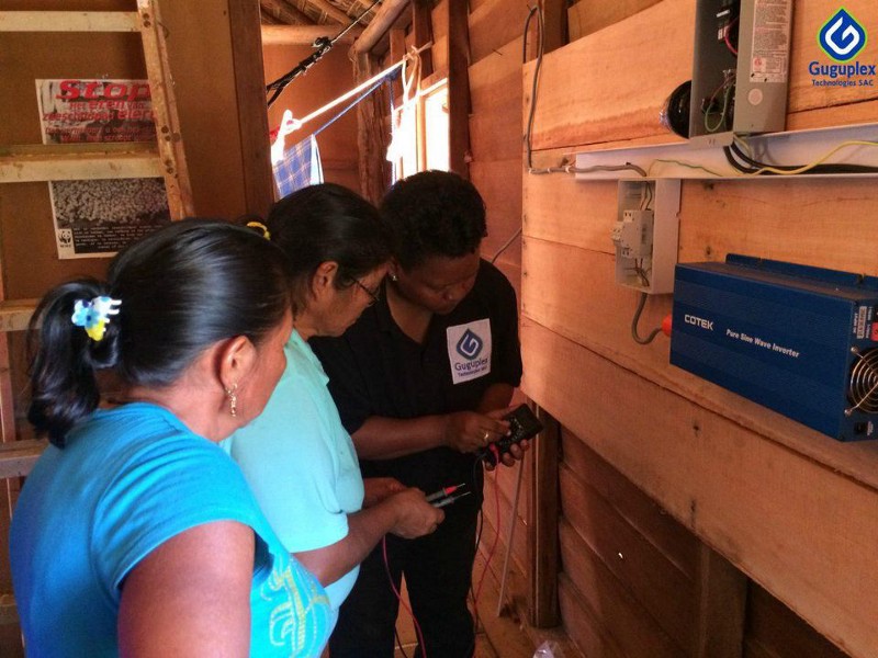 Three individuals examine an electrical component