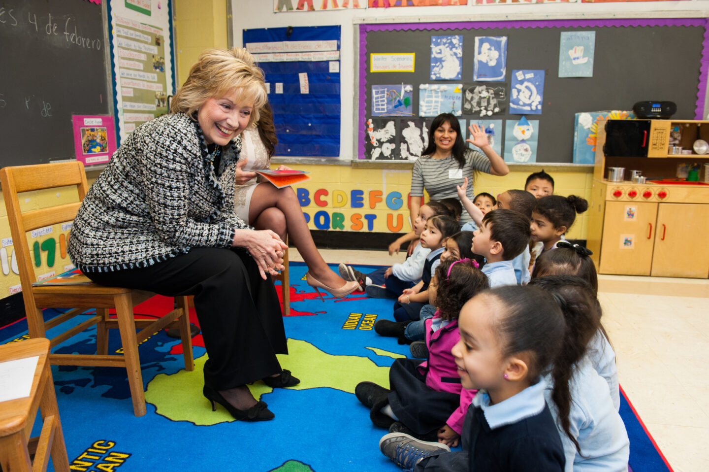 Secretary Clinton sits with a group of students in a classroom.