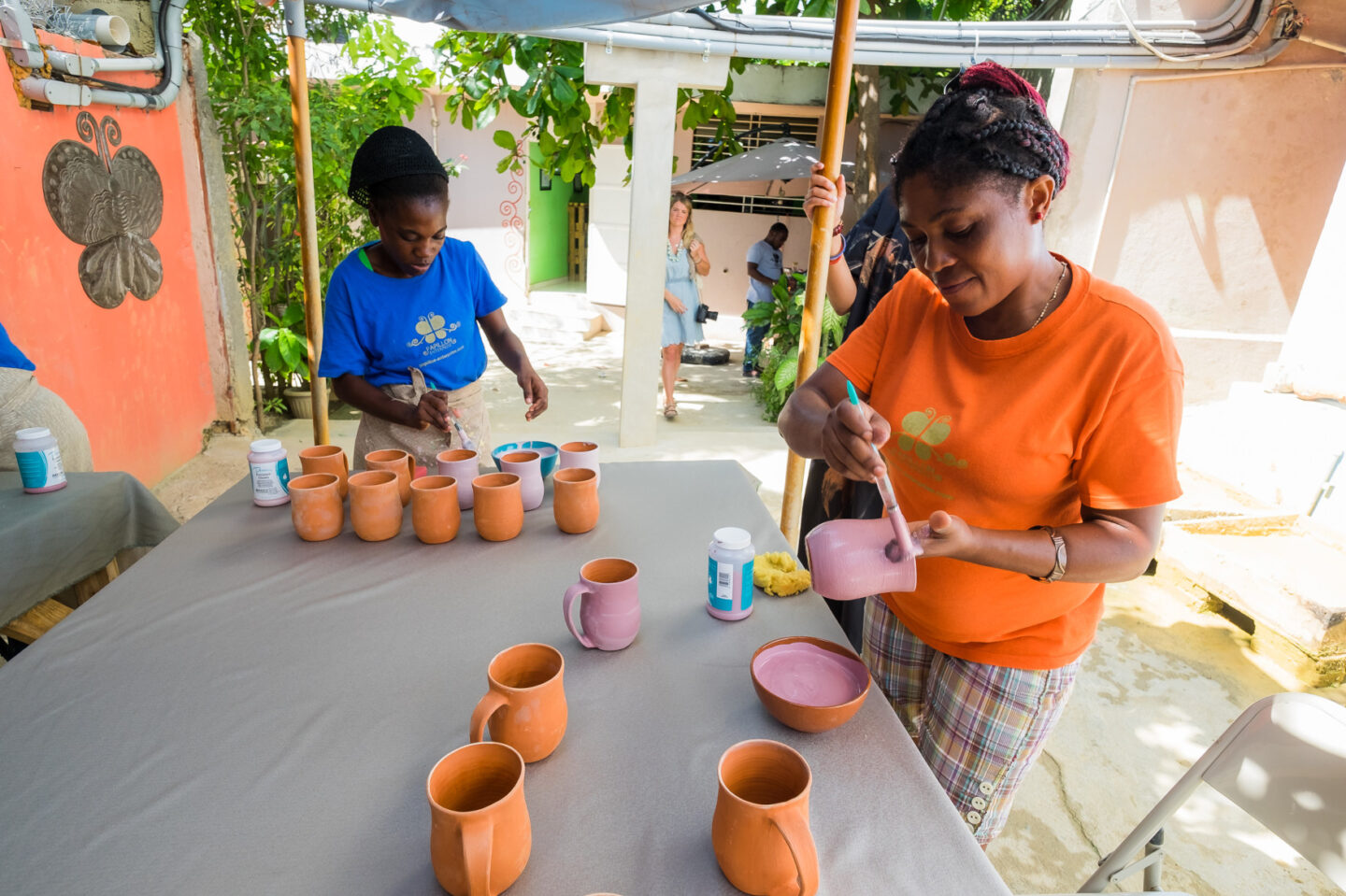 Two individuals paint pieces of pottery