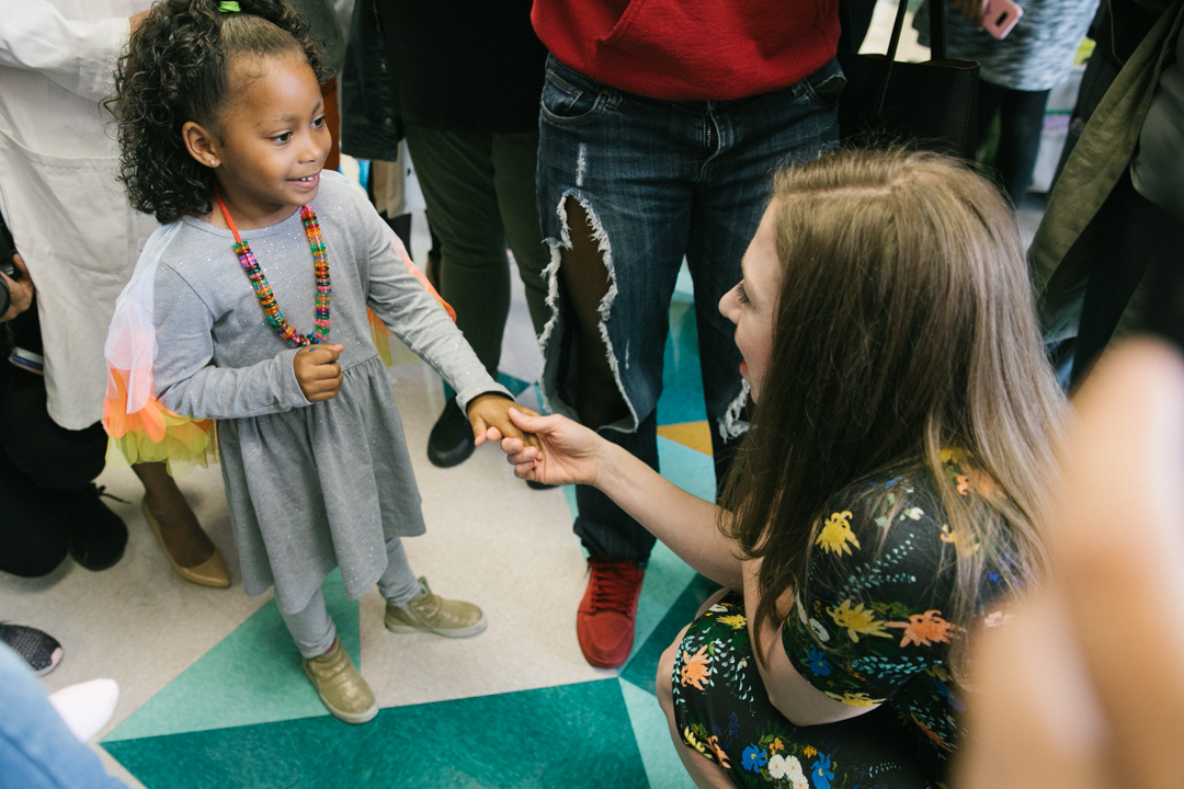 Chelsea Clinton kneels down to shake the hand of a child