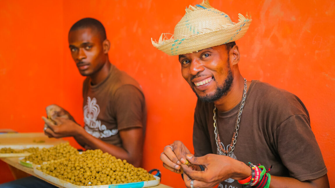 Two individuals put together artisan pieces using beads