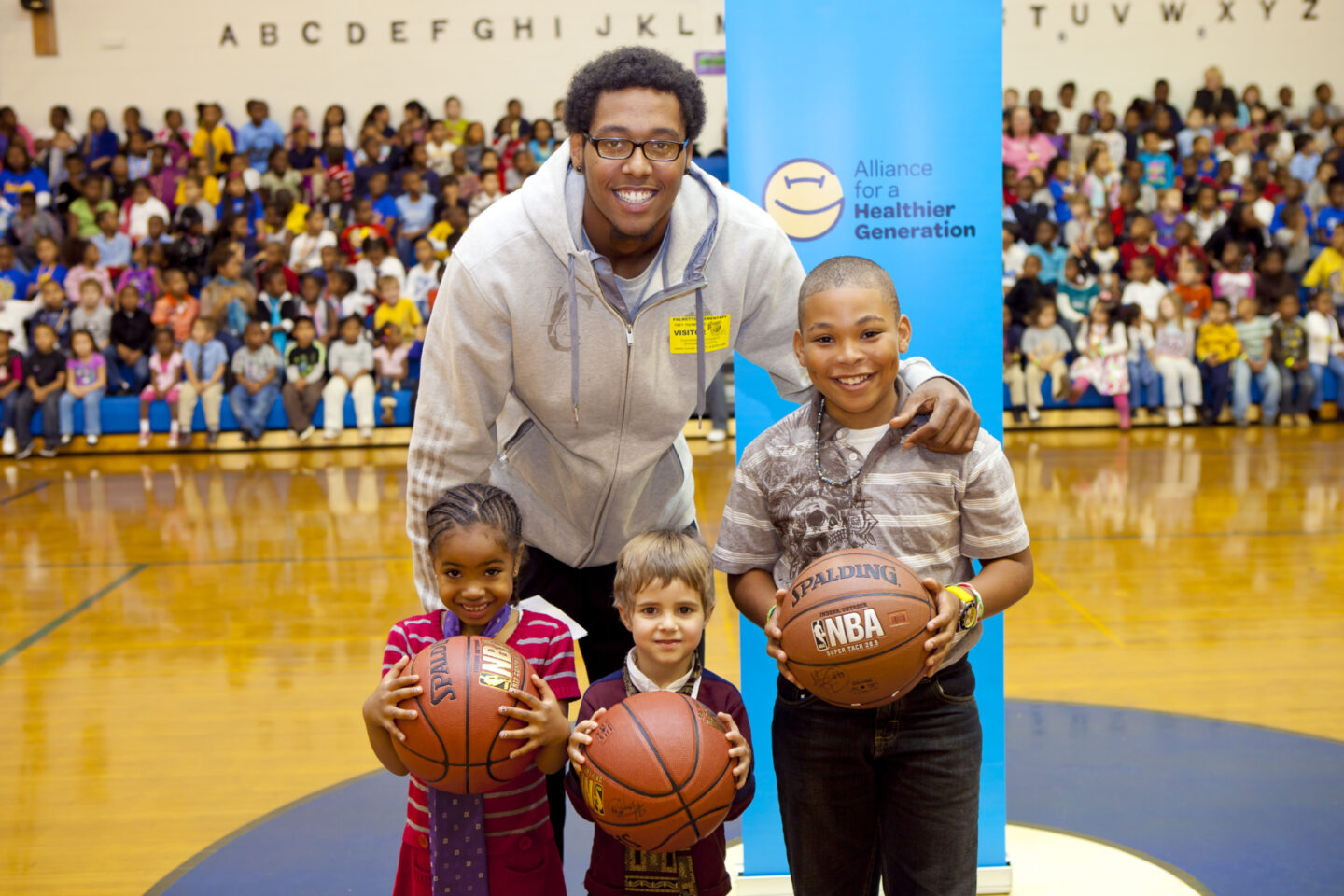 A professional basketball player takes a photo with students at an elementary school in Georgia