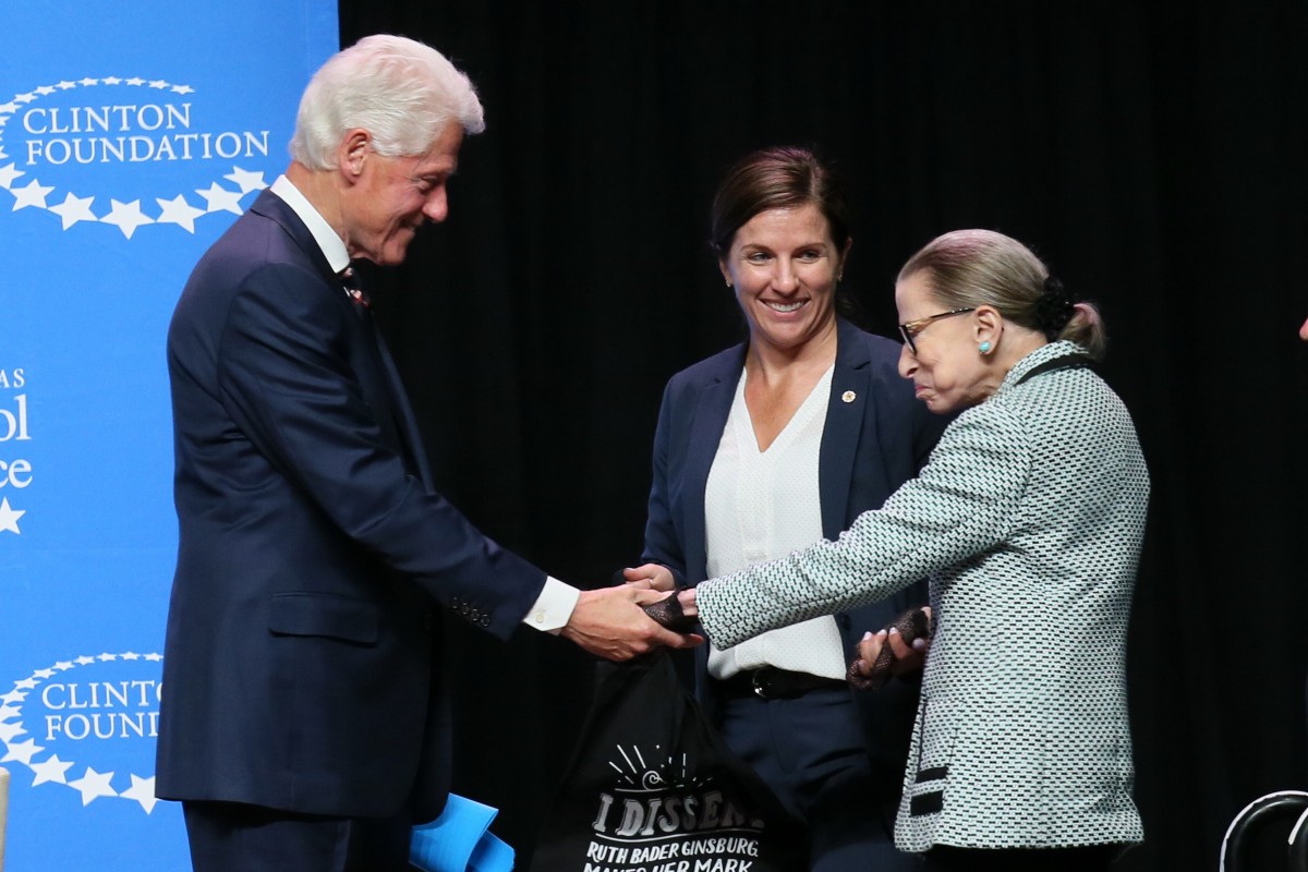 President Clinton and Ruth Bader Ginsburg shake hands while standing onstage