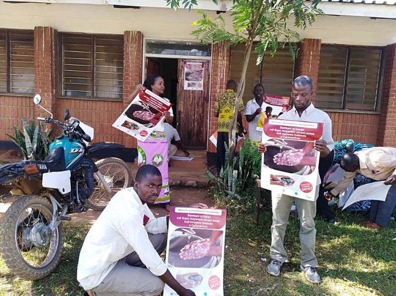 Individuals hold up posters about hand washing