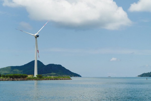A wide shot of a wind turbine on an island