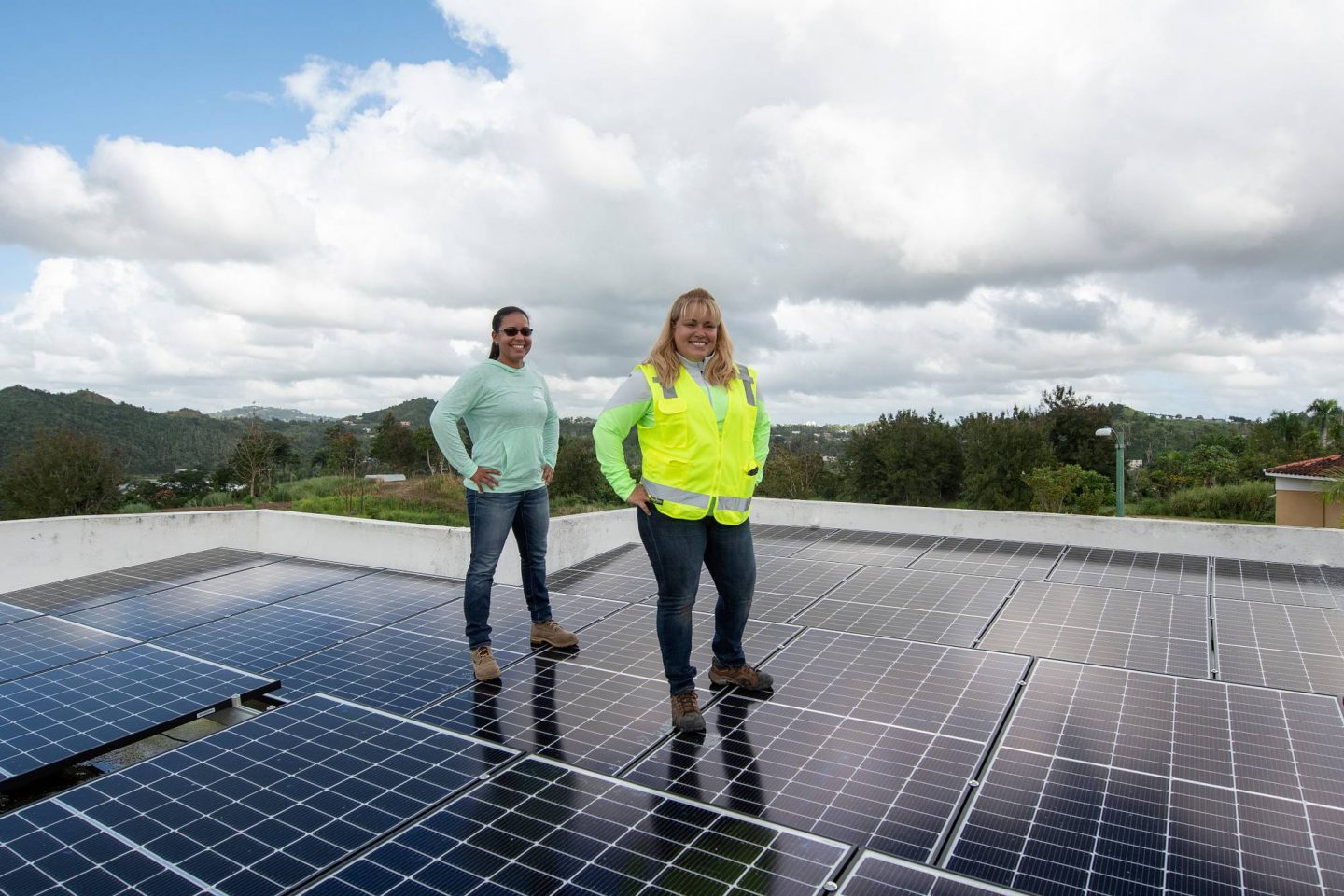 Two individuals stand atop solar panels