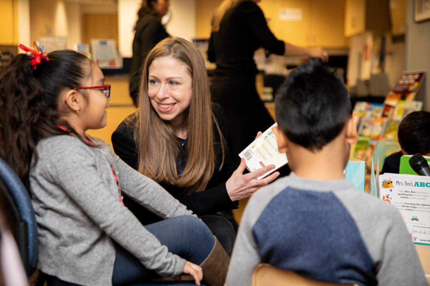 Chelsea Clinton and a child read a book together