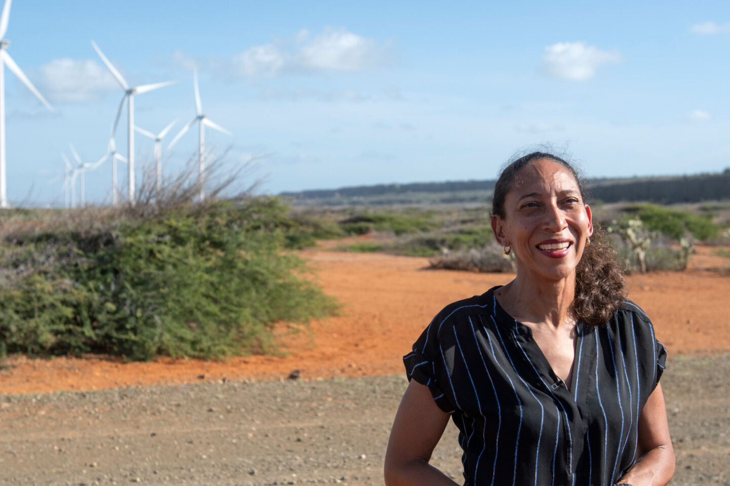 A woman stands underneath a wind turbine in Curaçao