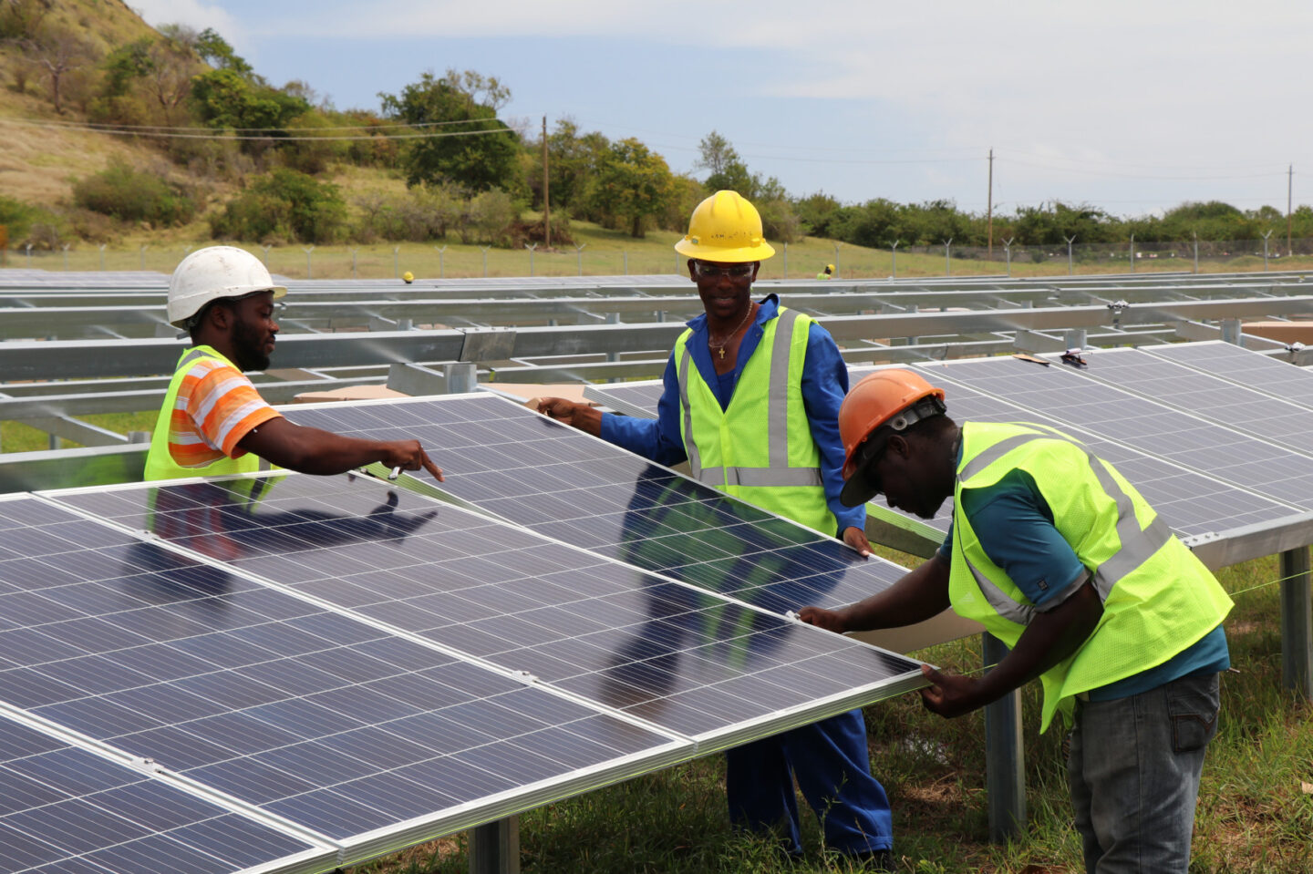 Workers install a solar panel at a solar farm in St. Lucia