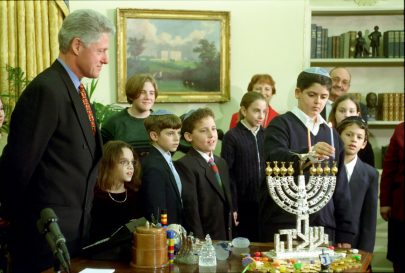 President Clinton and a group of children stand behind a menorah