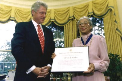 President Clinton stands with Rosa Parks in the Oval Office. Rosa Parks holds the Presidential Medal of Freedom certificate.