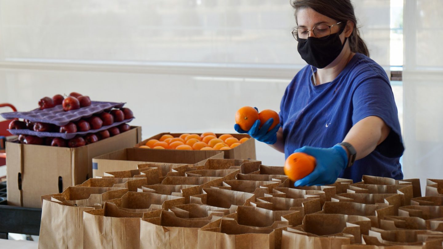 A Clinton Center team member puts fruit in sack lunches for those impacted by the pandemic