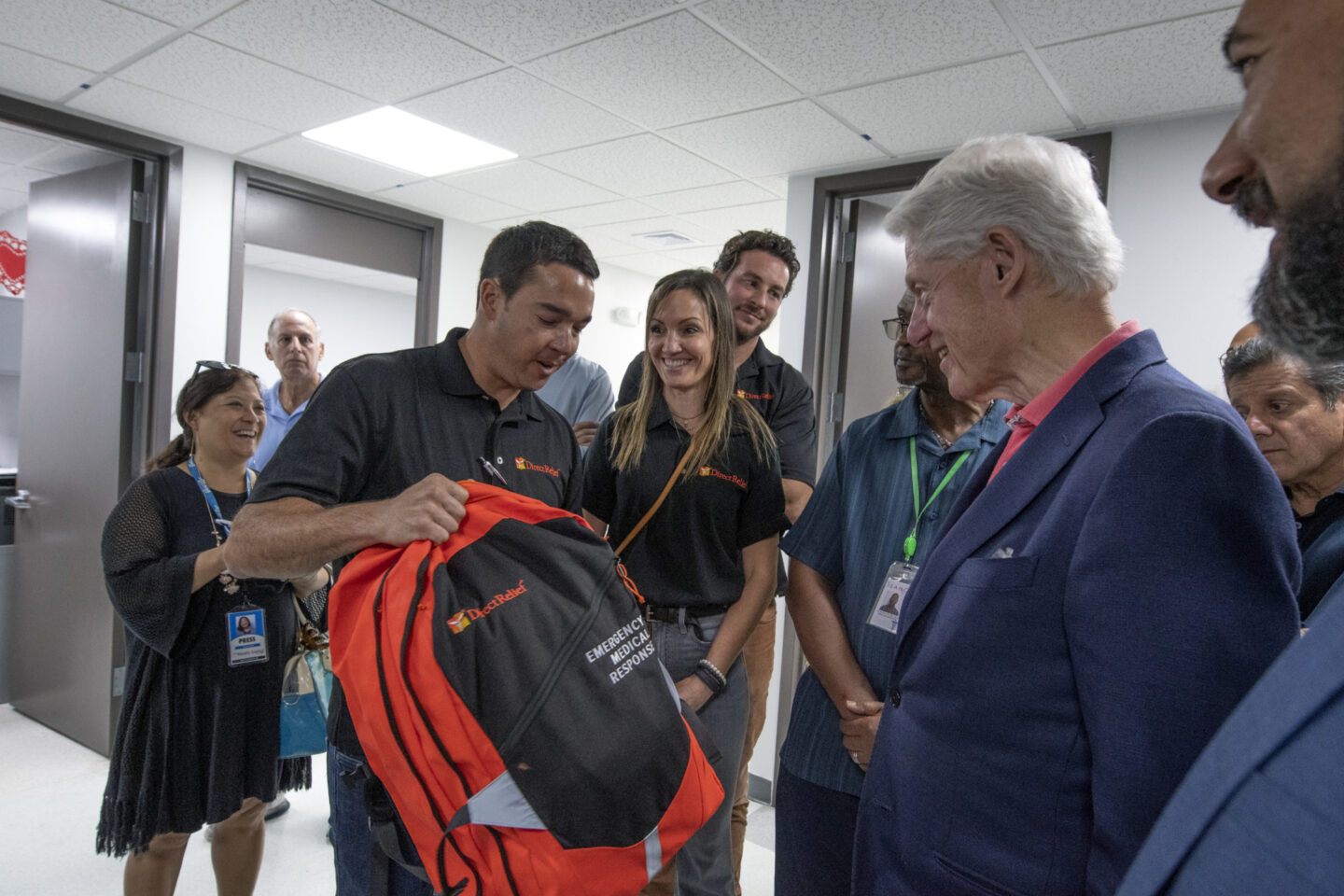 President Clinton speaks with an individual holding a backpack that says "emergency medical response"