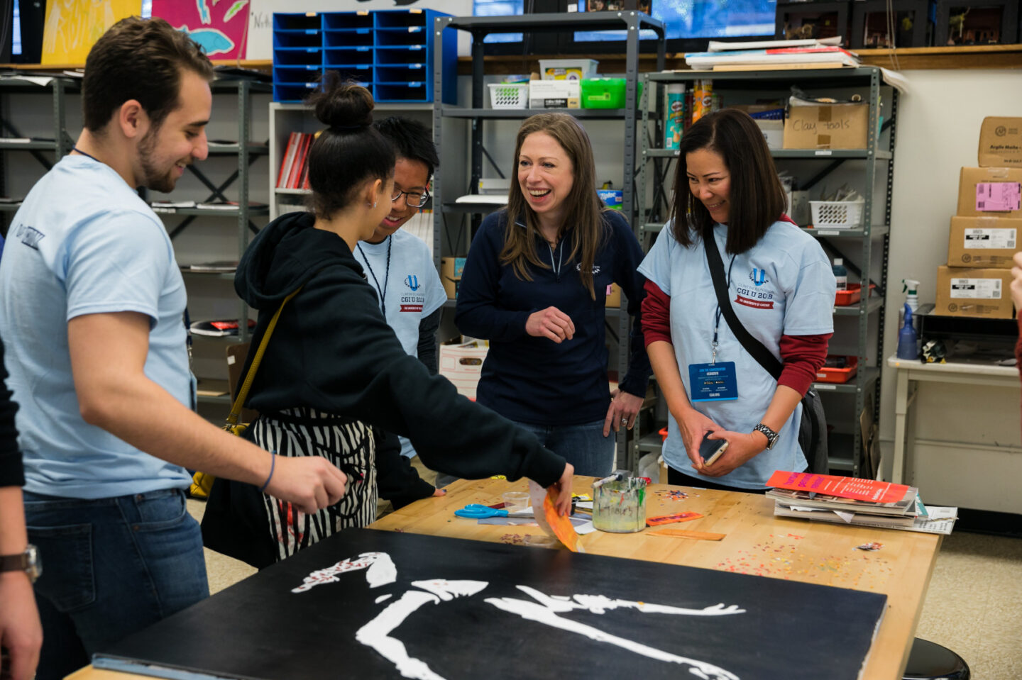 Chelsea Clinton and volunteers stand over an art project