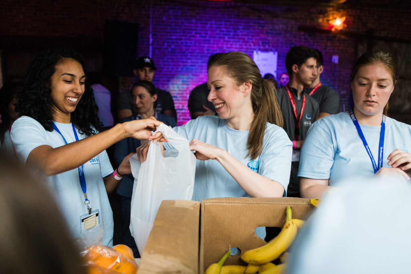 Chelsea Clinton and volunteers put produce into bags at a volunteer event
