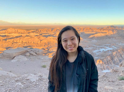 A CGI U student stands outside at sunset