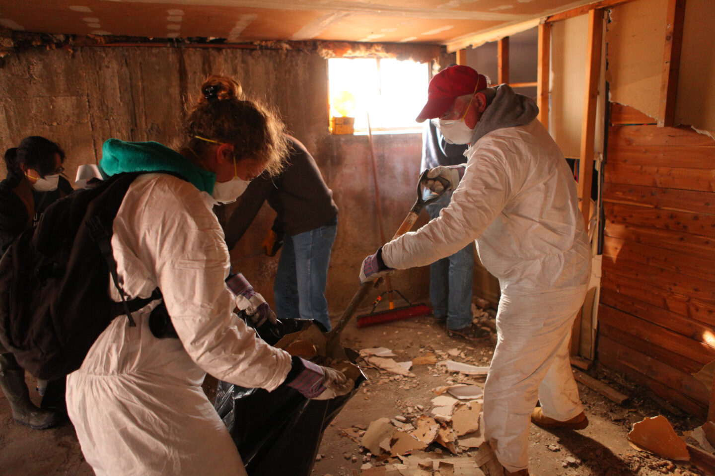 Volunteers wearing masks clear debris into a bag