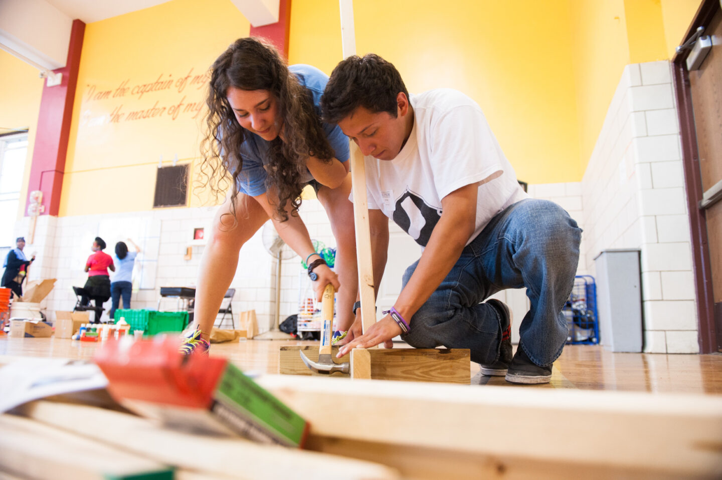 Volunteers hammer a piece of wood