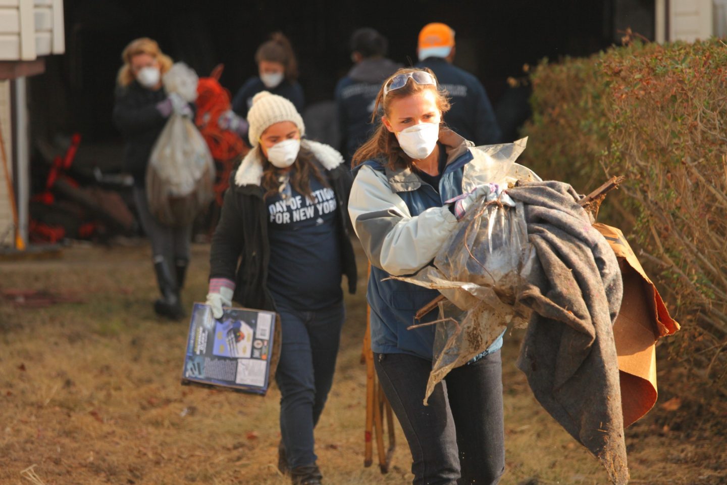 Volunteers carry armfuls of debris from Hurricane Sandy
