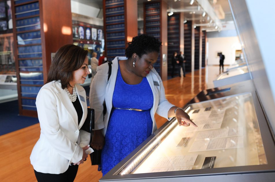 Two individuals examine a document on display at the Clinton Presidential Library