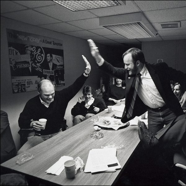 A group of individuals sit around a table and two are high-fiving