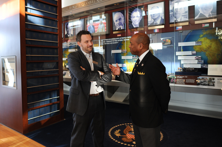 Two individuals converse in front of an exhibit at the Clinton Presidential Library