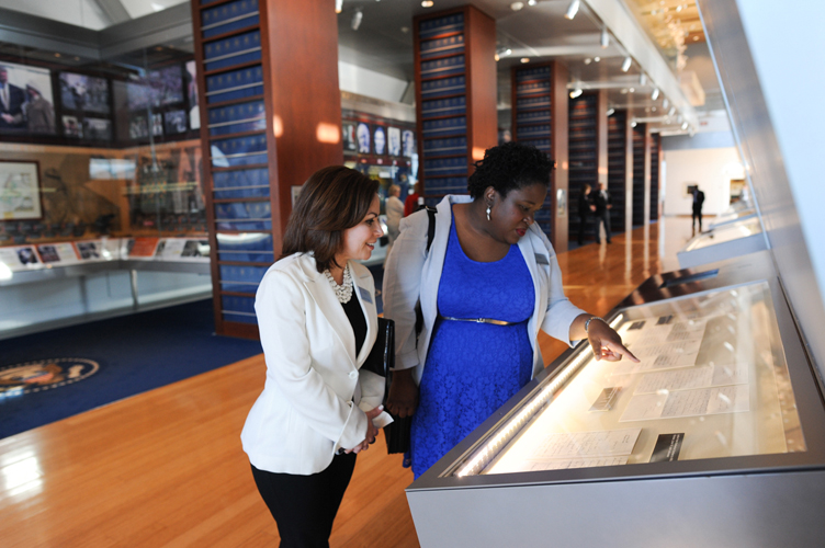 Two individuals examine a document in an exhibit at the Clinton Presidential Library