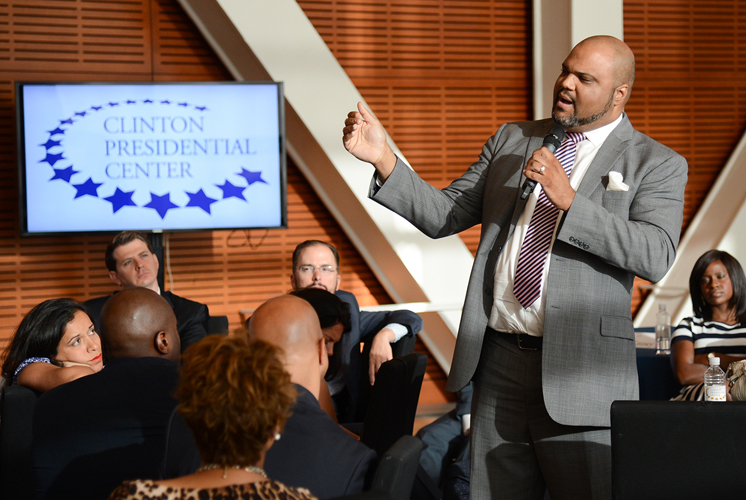 An individual speaks into a microphone while presenting to a group