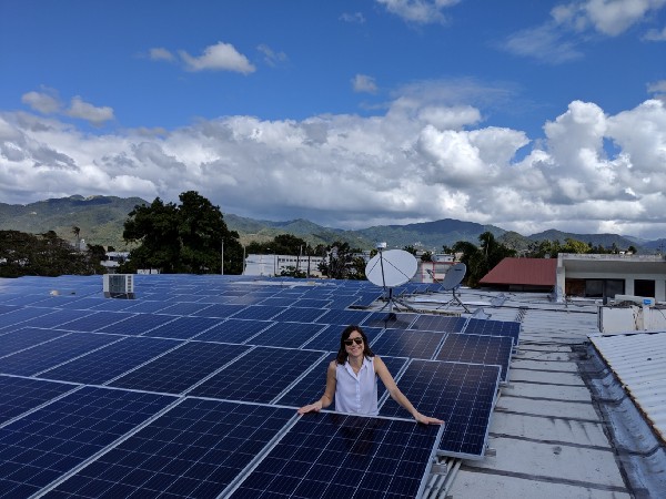 Sanya Detweiler stands amid several rows of solar panels