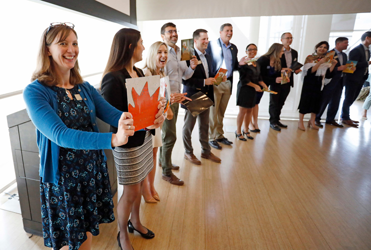 Individuals stand in a semi-circle holding up papers