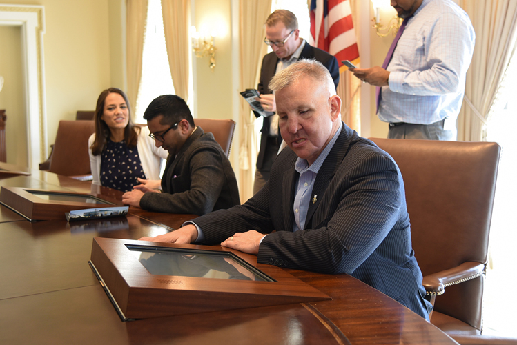 An individual seated in a replica of the Cabinet Room at the Clinton Presidential Center