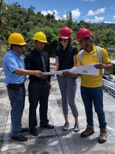 Several individuals wearing hard hats examine a document