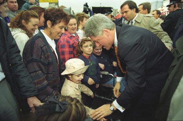 President Clinton shakes a child's hand as they stand amid a crowd
