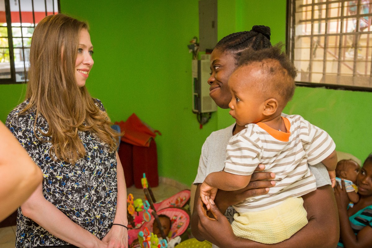 Chelsea Clinton speaks with an individual holding a young child