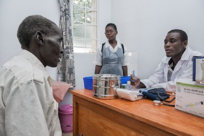 Three individuals speak in a medical facility