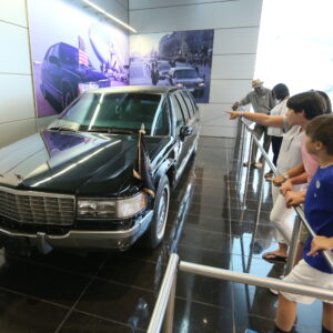 Clinton Center visitors look at a presidential limousine on display in the lobby of the museum