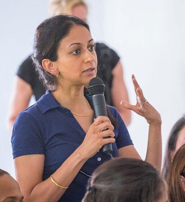 An individual stands and speaks into a microphone