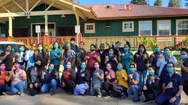 Large group of people take a photo together wearing face masks