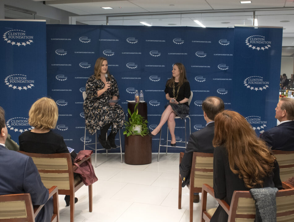 Chelsea Clinton and a staff member speak in front of a group of individuals