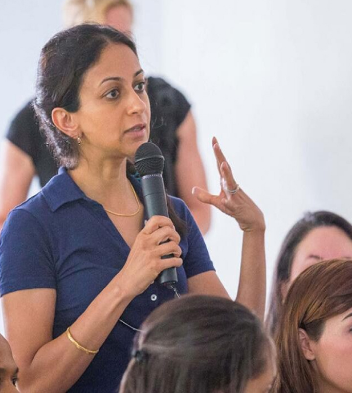 An individual stands and speaks into a microphone