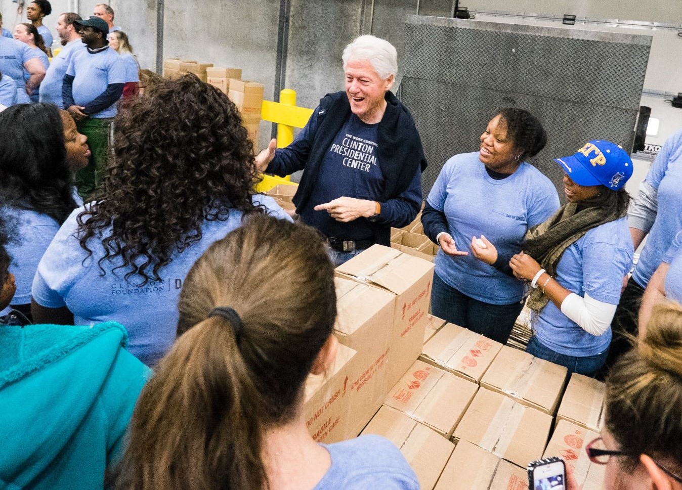 President Clinton and group of volunteers gather around boxes
