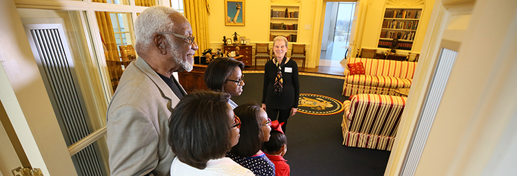 A family stands in the doorway of a full-size replica of the Oval Office at the Clinton Presidential Center