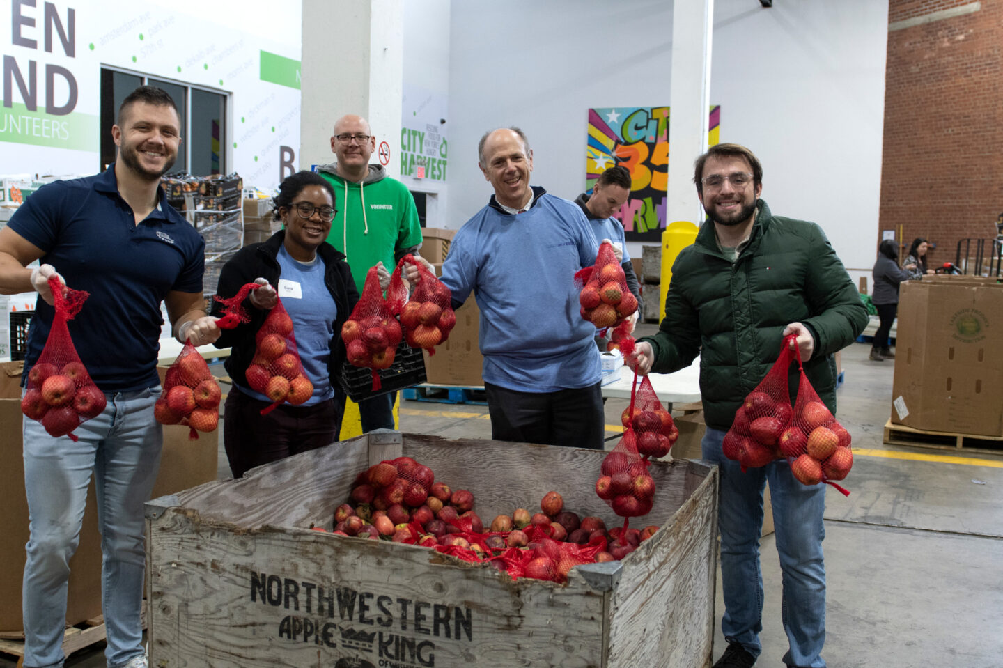 Staff and volunteers hold up containers of apples